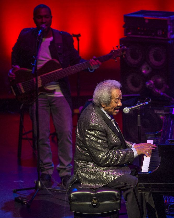 A closer view of Allen Toussaint. He is lit with a front special. There is a red cyc groundrow and a dim magenta back light.