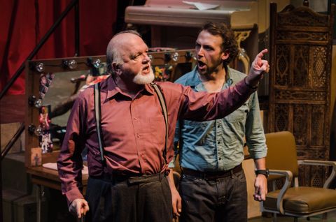Two actors stand in the dressing area of the backstage space for the show Dove. 
