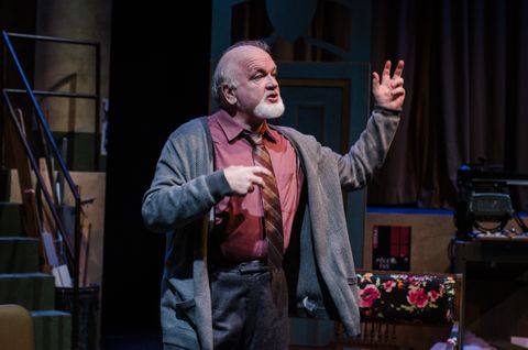 An older actor contemplates how he will die on stage. He is scuplted by warm front light from one side and a cool fill from the other. His surroundings are dimly lit pulling the focus to him.